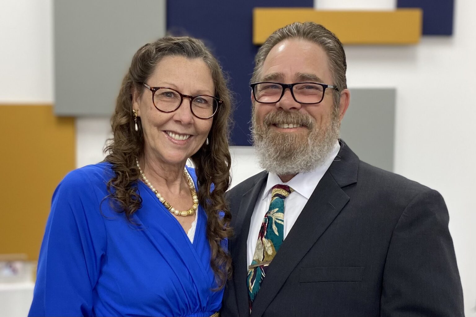 Smiling couple posing together indoors, dressed formally.