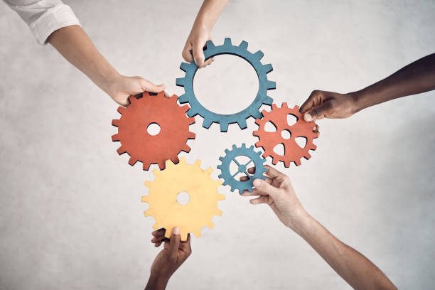 Hands holding interlocking colorful gears together.