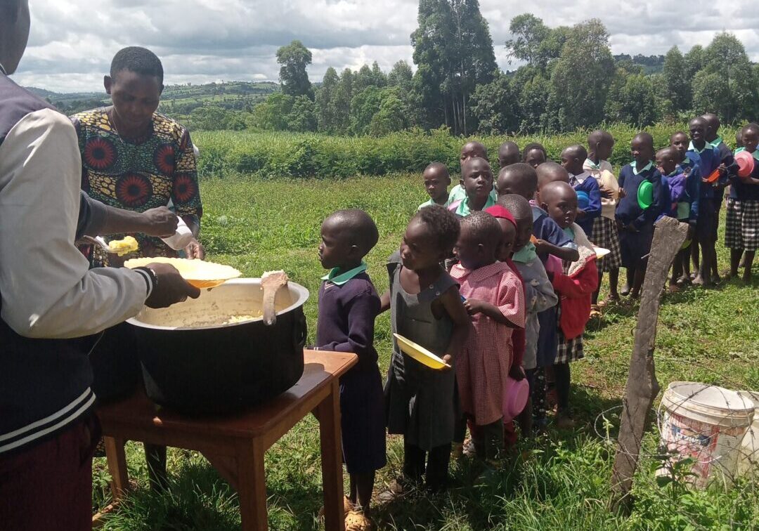 Children and adults gather outdoors for a communal meal distribution.